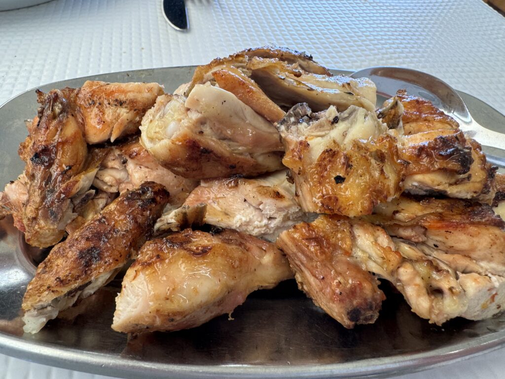 Traditional piri piri chicken meal with chargrilled chicken, fries, tomato and onion salad, and spicy piri piri sauce in an Algarve restaurant